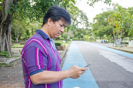 Asian man using smartphone while crossing roadの写真素材