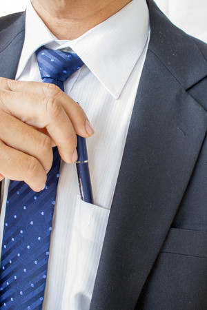 business man pulling or putting blue pen in his pocketの写真素材