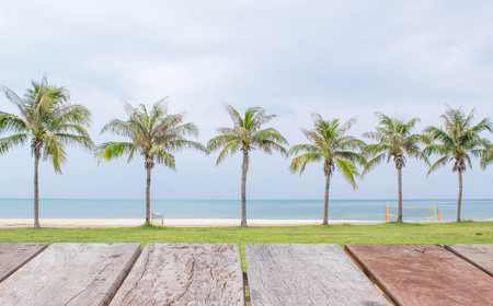Empty perspective wood over palm tree on the beach background, for product display montage