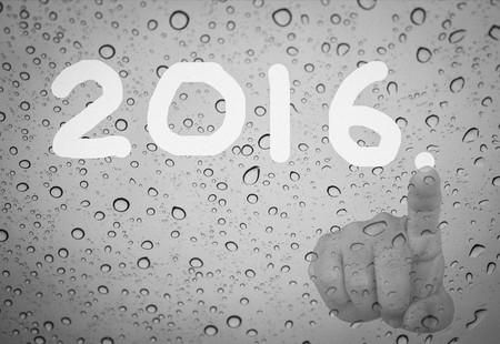 man hand write 2016 number on wet window