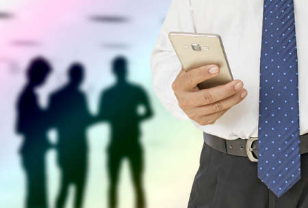 businessman using smart phone on background of silhouette photo people in the office