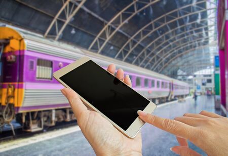 hand using smart phone with blur background photo of train at the stationの写真素材