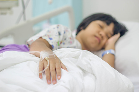 Asian patient kid with saline solution in hospital bedの写真素材