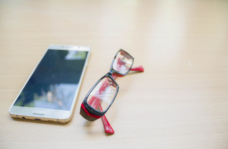 smart phone and glasses on wood tableの写真素材
