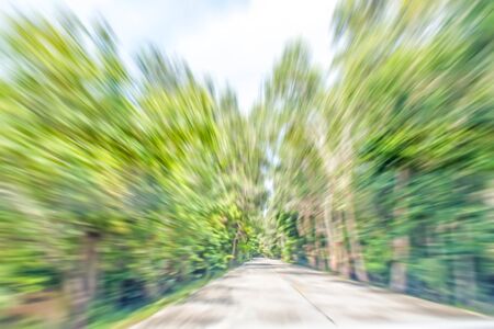abstract motion blurred photo of road along natural gree tree