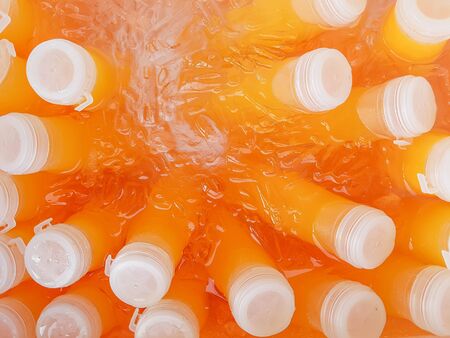 abstract photo of pure orange juice in white plastic bottlesの写真素材