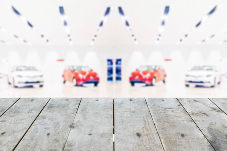 Empty perspective grungy wood table top texture on blurred car showroom background: for product display montageの写真素材