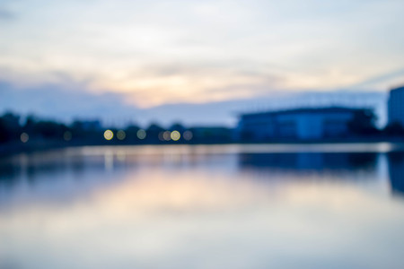 blurred background of city office building with bokeh light and water reflection during twilightの写真素材