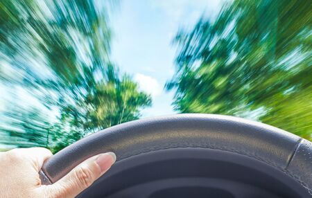 hand of woman driving car on blurrd fast motion nature roadの写真素材
