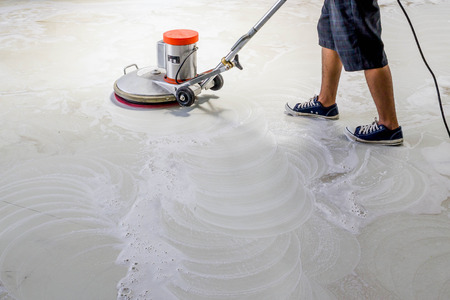 worker using scrubber machine for cleaning and polishing floorの写真素材