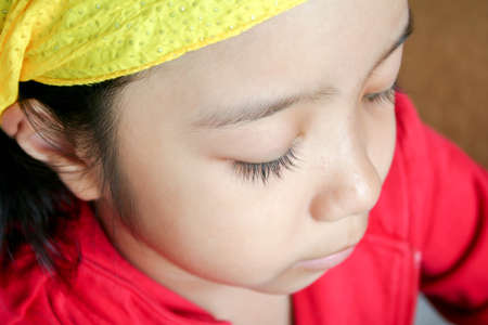 Asian kid with black hair and long eyelash looking at somethingの写真素材