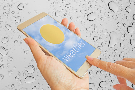 hand use smart phone on abstract  water drop background : concept for weather application on smart phoneの写真素材