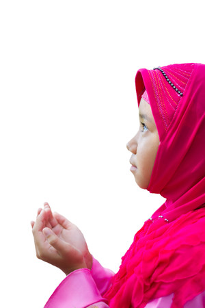 little Asian Muslim kid girl in pink hijab (Muslim scraft) praying on nature bokeh background with soft sunlightの写真素材