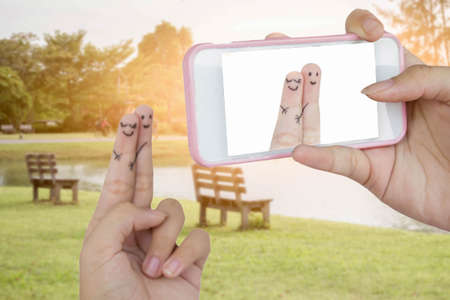 hand use smart phone take photo funny finger lovers on  natural green park backgroundの写真素材