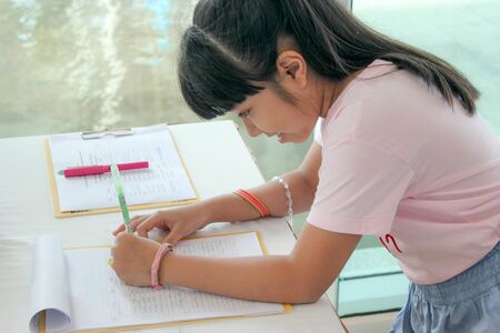 happy Asian kid writing with left hand