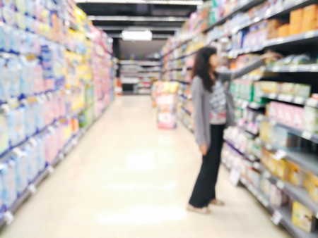 woman looking at supermarket shelf in blurry : for background useの写真素材