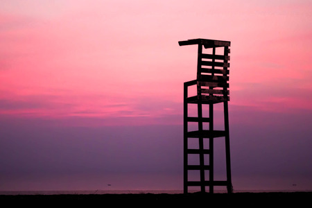 life guard chair on the beach with abstract blurred background of red skyの写真素材