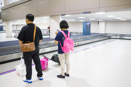passengers wait for baggage at airport carousel behind the wait lineの写真素材