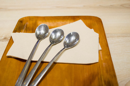 silver spoon on wood plate and wood table