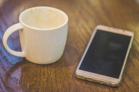 mobile phone with cup of coffee on wood tableの写真素材