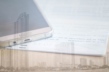 double exposure of mobile phone and book bank with city buildingの写真素材