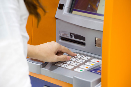 woman pushing on pin button of money machineの写真素材