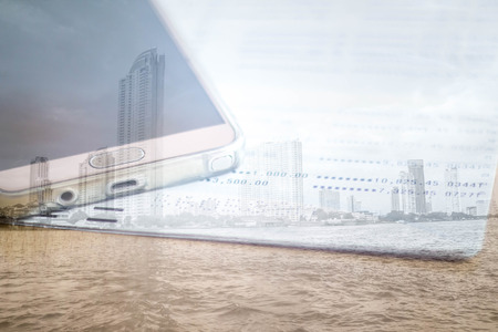 double exposure of mobile phone and book bank with city buildingの写真素材