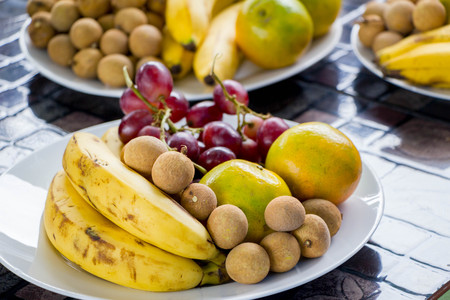 banana, orange, grape and longan in white plateの写真素材