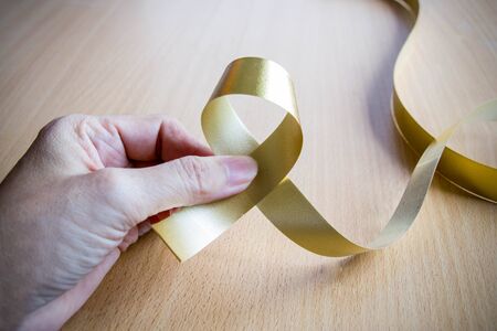 hand hold gold ribbon on wood tableの写真素材