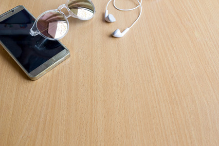 mobile phone, sun glasses and head phone on wood tableの写真素材