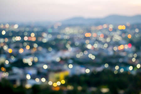 abstract blur bokeh of night light city with mountain and sunset sky backgroundの写真素材