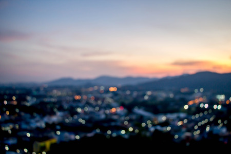 abstract blur bokeh of night light city with mountain and sunset sky backgroundの写真素材
