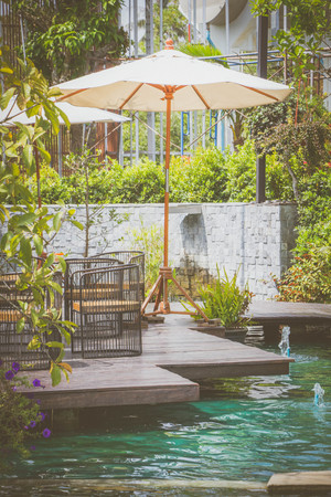 white umbrella with luxury chairs and the pond in garden