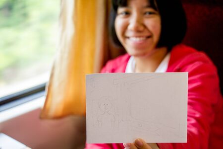 Asina girl in pink shirt showing her sketchの写真素材