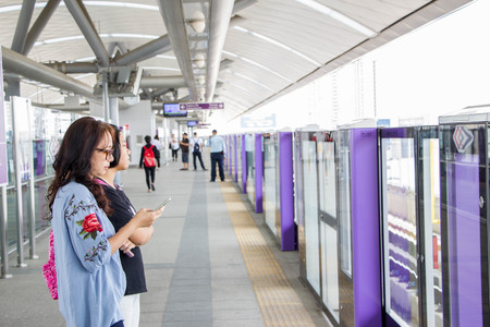 people using mobile phone when waiting for BTS (sky train) in Thailandのeditorial素材