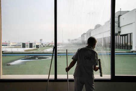 man worker cleaning window glass at the airportの写真素材