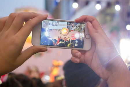 hand holding smart phone on blurred music band background