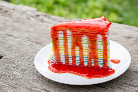 rainbow crape cake with strawberry sauce in white plateの写真素材