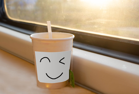 hot tea in paper cup on the table near window with sunlightの写真素材