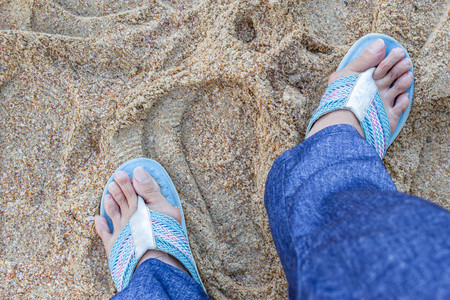 Hallux valgus, woman legs with bunions in trousers stand on sand backgroud