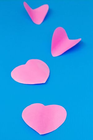 colored pink sheet of note paper, sticker note, note pad in heart shape Isolated on blue backgroundの写真素材