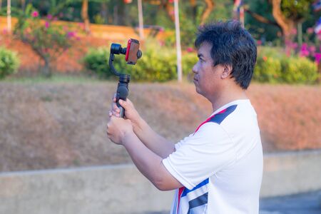Asian man taking photo on mobile phone with gimball