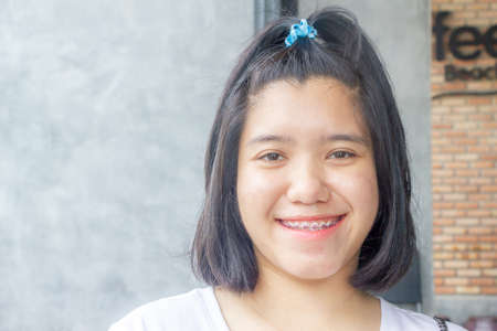 Asian teenager short hair smiling with pink braces on teeth