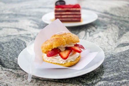 Choux cream, profiteroles with cream, and strawberry on white plate