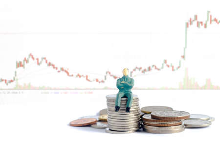 miniature businessman standing with pile of coins on stock graph background : concept of rich or wealthの写真素材