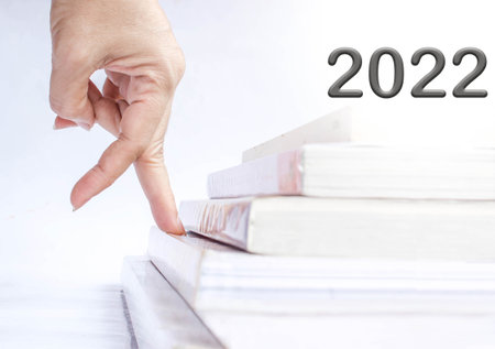 woman fingers walk on book steps up to 2020 : concept for New Year 2022の写真素材