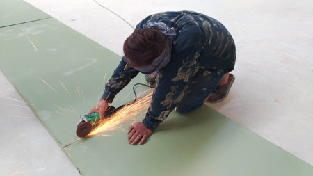 Construction local Thai worker uses a small steel cutter to cut the galvanized sheet to fit the...