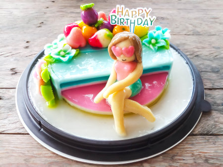 kanom Look Choup in lady figure shaped on coconut jelly cake for birthday: Thai traditional dessert deletable imitation fruits made from green been, coconut milk, sugar and jelly in fruit shape (look like Marzipan)の写真素材