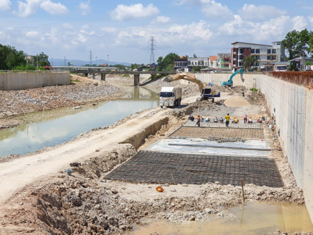 The backhoe was digging a ground to build an irrigation canal for sending the water to the sea, worker working on groundの写真素材