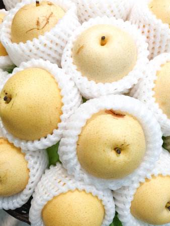 juicy and fresh yellow nashi pear or asia pear, Pyrus pyrifolia, wrapped in white mesh protective foamの写真素材